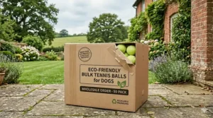 A sturdy cardboard box labelled for wholesale delivery containing a 50-pack of eco-friendly tennis balls for dogs.