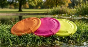 Three different fabric frisbees for dogs displayed in high-visibility orange, pink, and yellow to ensure they are easy to find in long grass.